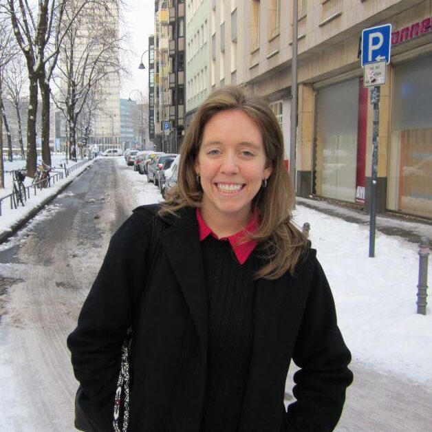 Jocelyn in a black jacket smiling and standing on a snowy road